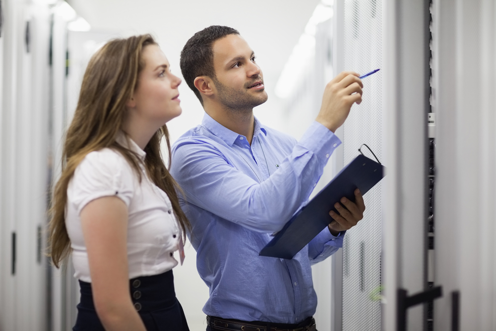 Technicians with clipbard looking at servers in data center-1